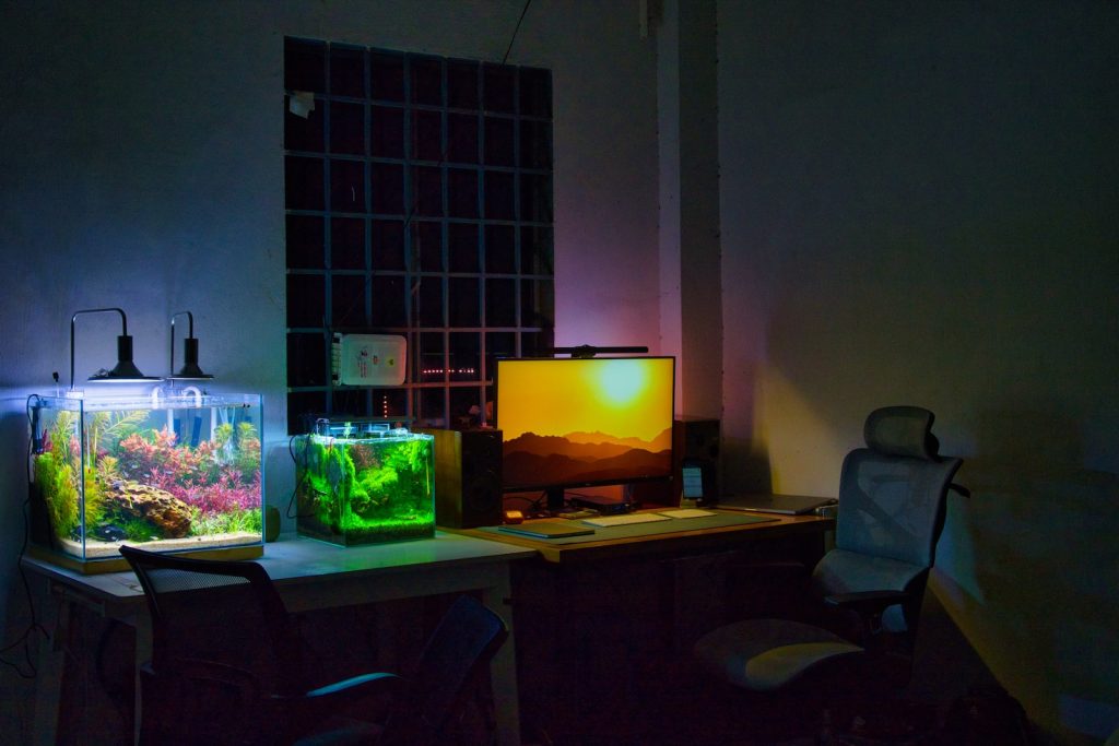 a desk with a computer and a fish tank